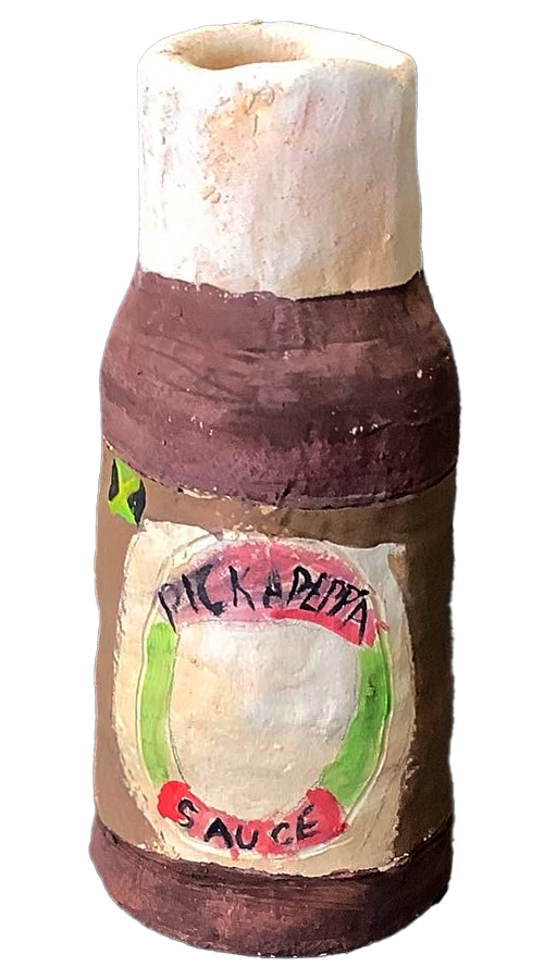A handmade clay condiment bottle featuring a painted label with the text 'Pick a Pitta Sauce'. The bottle has a textured brown base and a light-colored top.