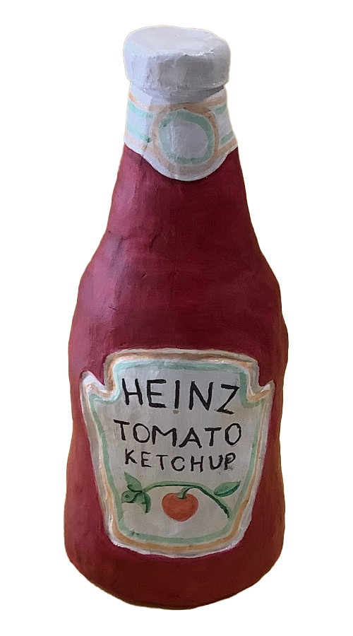 A clay sculpture of a Heinz tomato ketchup bottle, painted red with a label displaying the text 'HEINZ TOMATO KETCHUP' and a simple illustration of a tomato.