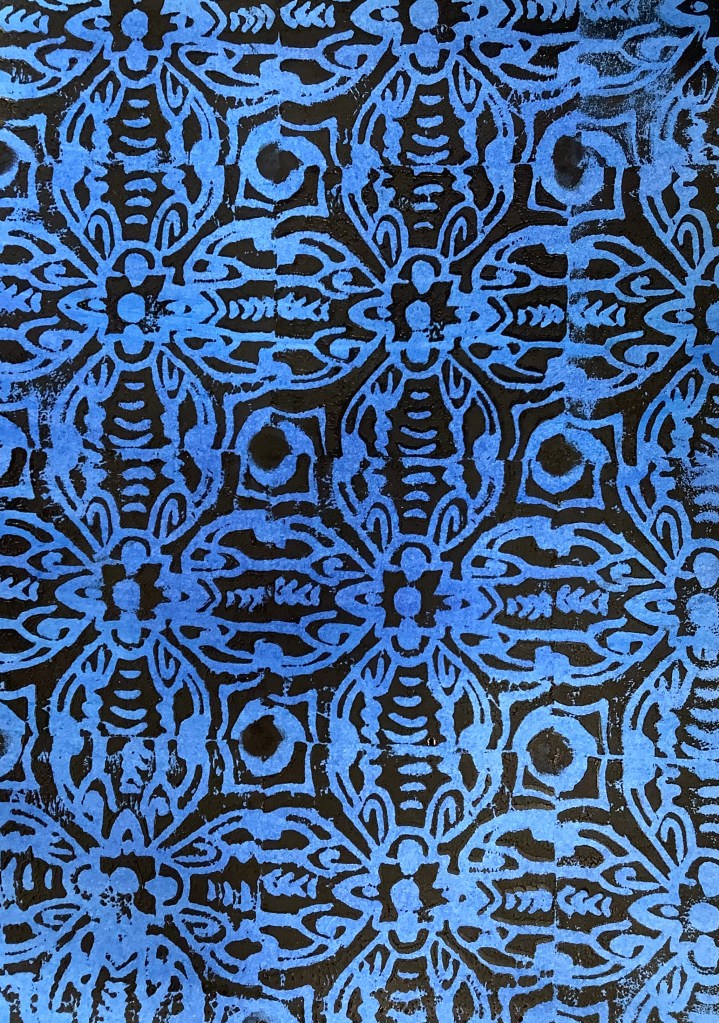 Close-up of a printed pattern in blue and black colors, featuring intricate designs and shapes, typical of a printmaking project.