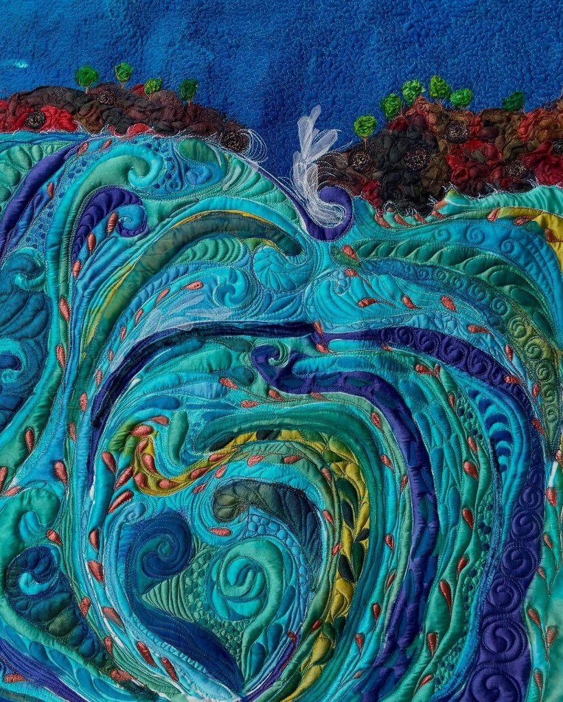 Michelle Mischkulnig - Close-up view of a vibrant textile artwork depicting swirling waves, showcasing intricate stitching and layers of rich blue, green, and turquoise fabrics, along with subtle earthy tones in the background.