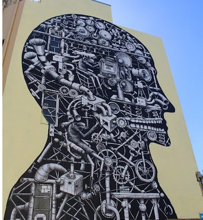 A large-scale mural depicting a profile silhouette filled with intricate mechanical and industrial patterns, showcasing a blend of surreal and imaginative elements.