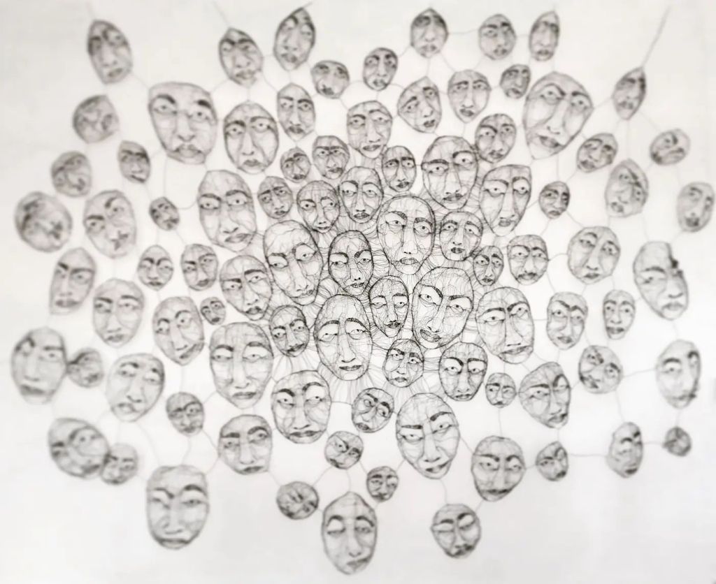 An abstract wire sculpture featuring numerous human faces interconnected, showcasing intricate details and varying expressions that evoke a sense of community and emotion.