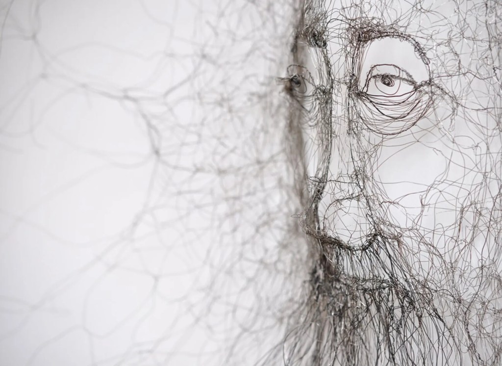 Close-up view of a wire sculpture depicting a human face, showcasing intricate details and layered wire formations that create a sense of depth and movement.