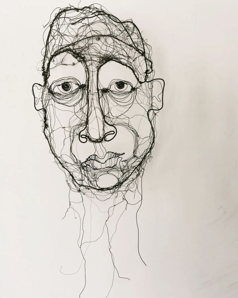 Wire sculpture of a human face, intricately crafted with layered wire, showcasing expressive features.