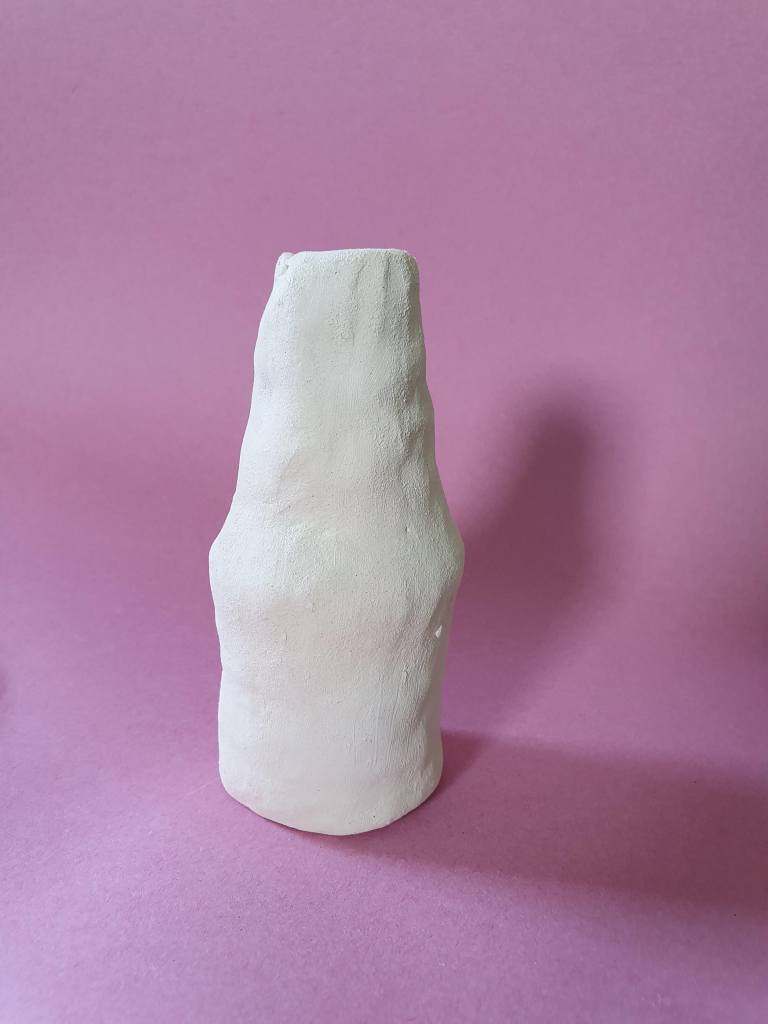 A handmade clay bottle with a textured surface, set against a pink background.